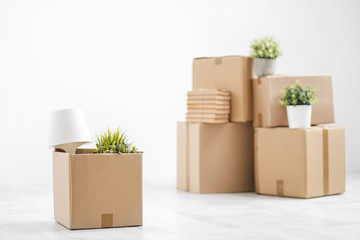 Cardboard boxes with things are stacked on the floor against the background of a white wall close...