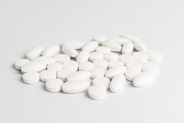 Fototapeta na wymiar Close up of a group of white pills on white background, in random order