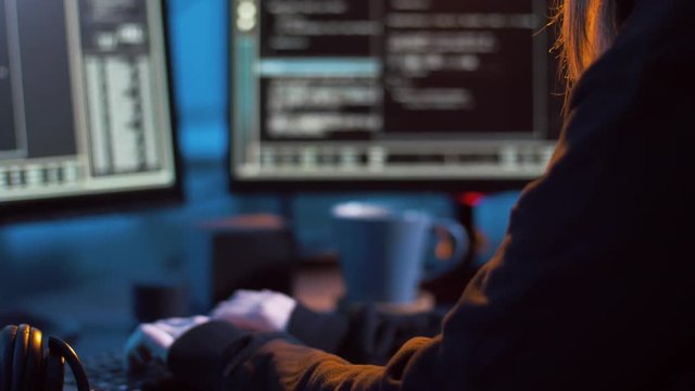 cybercrime, hacking and technology concept - female hacker in dark room creating code or using computer virus program for cyber attack