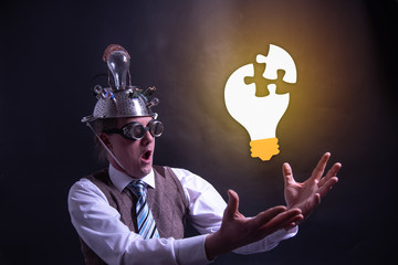 Funny nerd or geek with aluminium hat looking to light bulb having an idea - obrazy, fototapety, plakaty