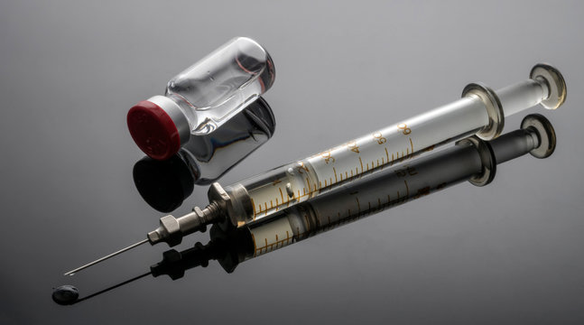 Vintage syringe next to vials with medication, conceptual image, horizontal composition