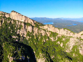 Aerial view of mountain with water reservoir  on the background. Mountain peak with beautiful blue sky and green forest. Landscape of mountain in natural reserve park. Miyun, Beijing, China.