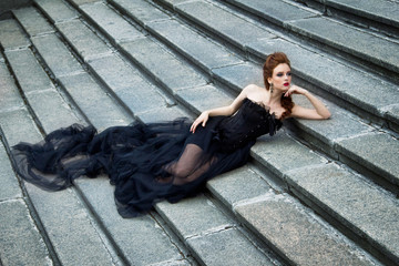 Art work Gothic fashion: a beautiful young girl in black dress and headwear sitting near castle....