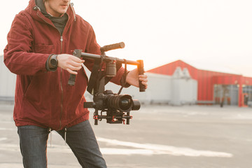 Сlose-up photo of a man of a videographer, holds in his hands a stabilizer and EVIL camera on the...