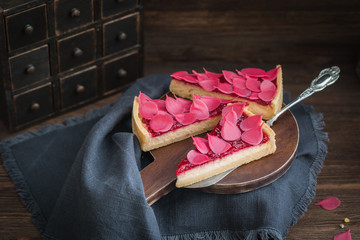 Homemade strawberry tart sliced on wooden plate on the rustic background
