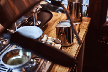 A mug with milk on a counter next to a coffee machine in a restaurant