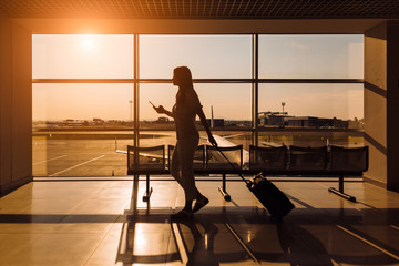 Fototapeta premium Traveler at the airport. Silhouette of a woman waiting a plane