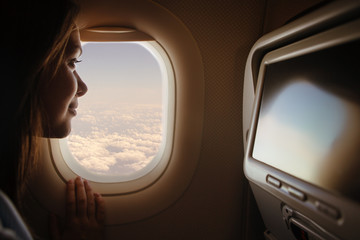 Woman looking through window in airplane 