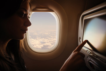Fototapeta na wymiar Woman in airplane using interactive touchscreen 