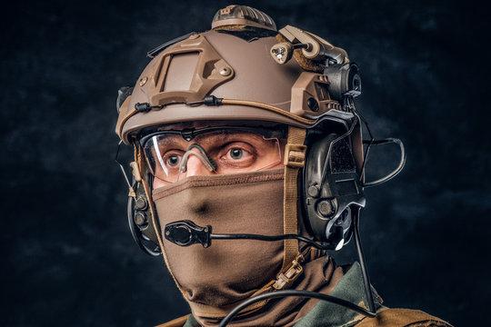 Close-up portrait. Private security service contractor in camouflage helmet with walkie-talkie. Studio photo against a dark textured wall