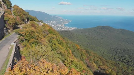 Aerial shot: mountain road and sea coastal town view at summer sunny day.