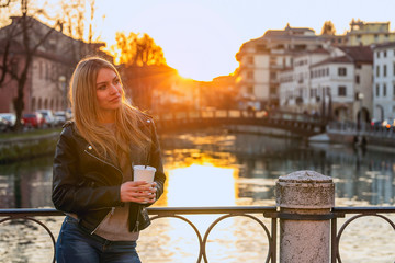 Young stylish woman drinking coffee to go in a city street 