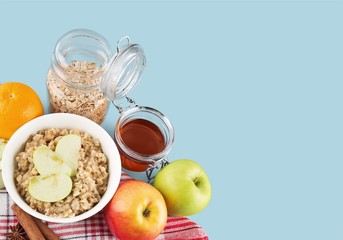 Raw oats in bowl and fruit salad, apples on the wooden table