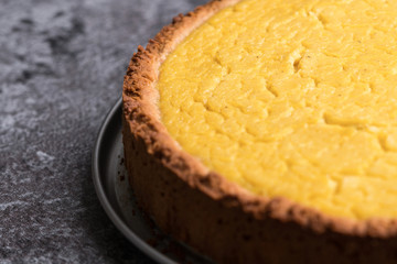 Tasty homemade vegan lemon cheesecake on dark gray stone plate