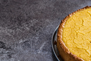 Tasty homemade vegan lemon cheesecake on dark gray stone plate