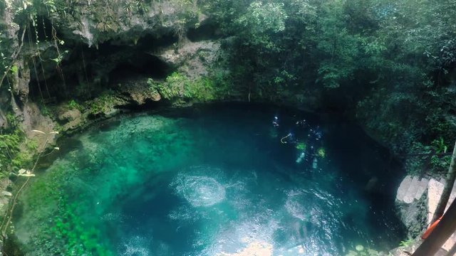 Stone stairway leading down the the Zapotec cenote pool with scuba divers in the water.
