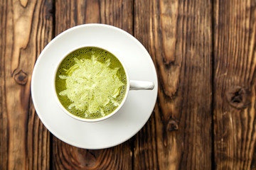 cup of hot matcha green tea latte on wood background