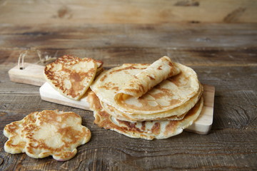  pancakes of different shapes on a board on a rustic wooden table with space for text