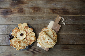 pancakes in the shape of a heart and flowers and pancakes on a board on a rustic wooden table with space for text. Flat lay. Top view.