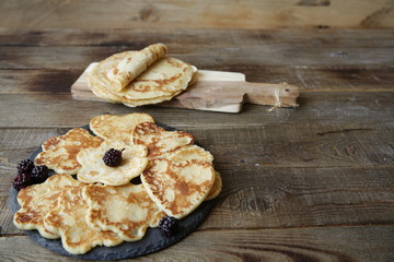pancakes in the shape of a heart and flowers and pancakes on a board on a rustic wooden table with space for text