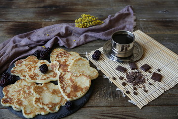 pancakes on a wooden rustic table with a cup of coffee and chocolate pieces. Shrovetide, carnival concept.