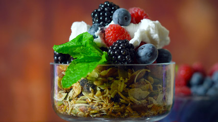 Grain free oat free paleo diet granola breakfast served with fresh seasonal berries, coconut milk, and coconut yoghurt.