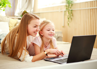 Happy family mother with daughter using computer laptop at home, modern lifestyle