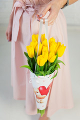 Womans hand holding bouquet of yellow tulips