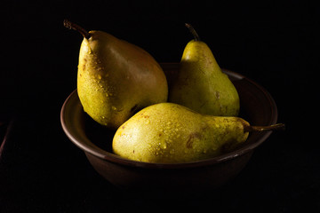 pears in a clay bowl with water drops