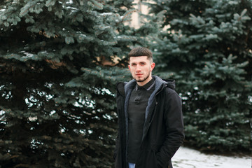 Half length portrait of young bearded guy in black coat