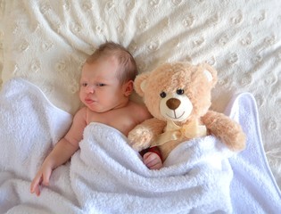  Sleeping newborn baby girl with a bear toy.Beautiful little baby girl with plush teddy bear