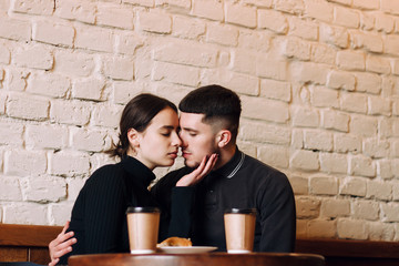 Sensual lovely couple sitting together by the table in cafe