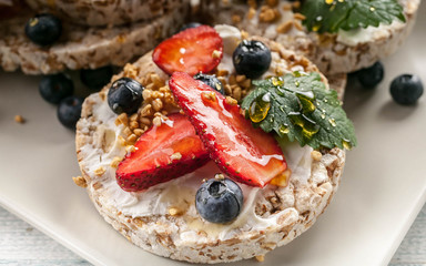 Close-Up puffed whole grain crispbread with curd cheese, honey, mint leaves, fresh strawberries and blueberries. Healthy food
