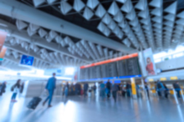 Inside of Airport with a lot of people. Airport interior with a flight information board. Blurred defocused image