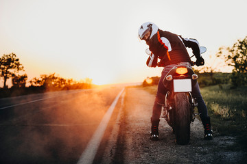 Amazing portrait of a caucasian biker sitting on his bike ready to go and looking into camera over...