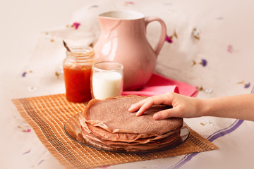 Many Russian-style thin pancakes with crispy crust served with cream and milk.