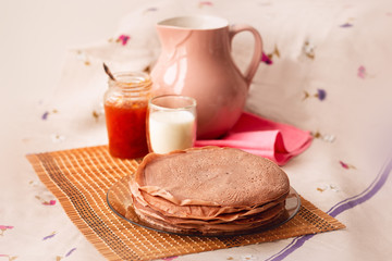 Many Russian-style thin pancakes with crispy crust served with cream and milk.
