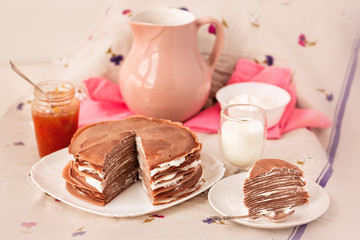 Many Russian-style thin pancakes with crispy crust served with cream and milk.