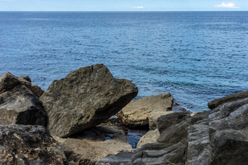 Fototapeta na wymiar Italy,Cinque Terre,Riomaggiore, a person sitting on a rock near the ocean