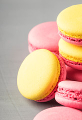 Pink yellow macaroons cakes on gray table background, place for text, trendy minimalism style, selective focus