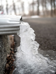 close view of frozen water falling from gutter