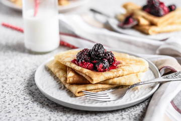 Pancakes with berries and honey on a gray background. Pancake week. Delicious breakfast of pancakes with jam.