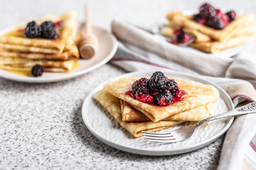 Pancakes with berries and honey on a gray background. Pancake week. Delicious breakfast of pancakes with jam.