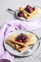 Pancakes with berries and honey on a gray background. Pancake week. Delicious breakfast of pancakes with jam.