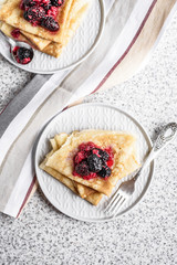 Pancakes with berries and honey on a gray background. Pancake week. Delicious breakfast of pancakes with jam.
