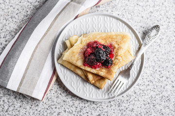 Pancakes with berries and honey on a gray background. Pancake week. Delicious breakfast of pancakes with jam.