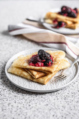Pancakes with berries and honey on a gray background. Pancake week. Delicious breakfast of pancakes with jam.