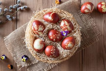 Fototapeta na wymiar Easter eggs dyed with onion peels, with a pattern of fresh herbs, in a basket
