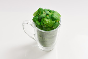 Mint leaves in a cup isolated on white background.