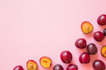 Beautiful, fresh whole and half of plums on pastel pink background. Healthy sweet food concept. Empty place for text or logo. 